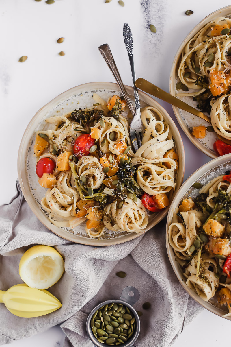 Creamy Fettuccine with Roasted Butternut Squash and Broccolini. Three plates filled with fettuccine pasta, creamy vegan sauce, roasted butternut squash, roasted grape tomatoes, and fresh roasted broccolini.