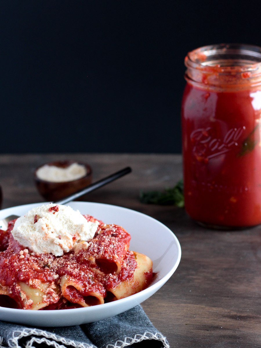 white plate with pasta and tomato sauce with ricotta on top.  Jar of sauce in background