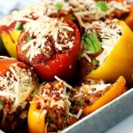 vegan stuffed peppers by pasta-based. six stuffed peppers together in a silver pan.