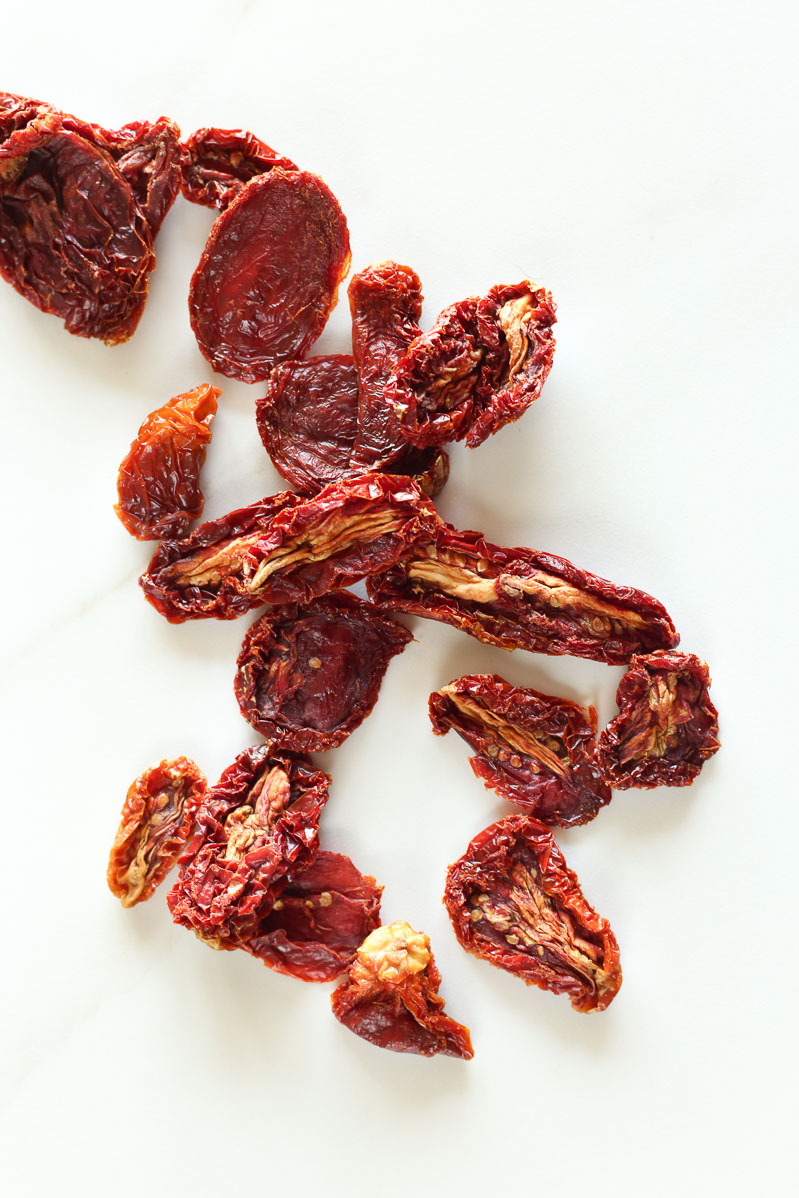 Bright red sun dried tomatoes scattered on a white table