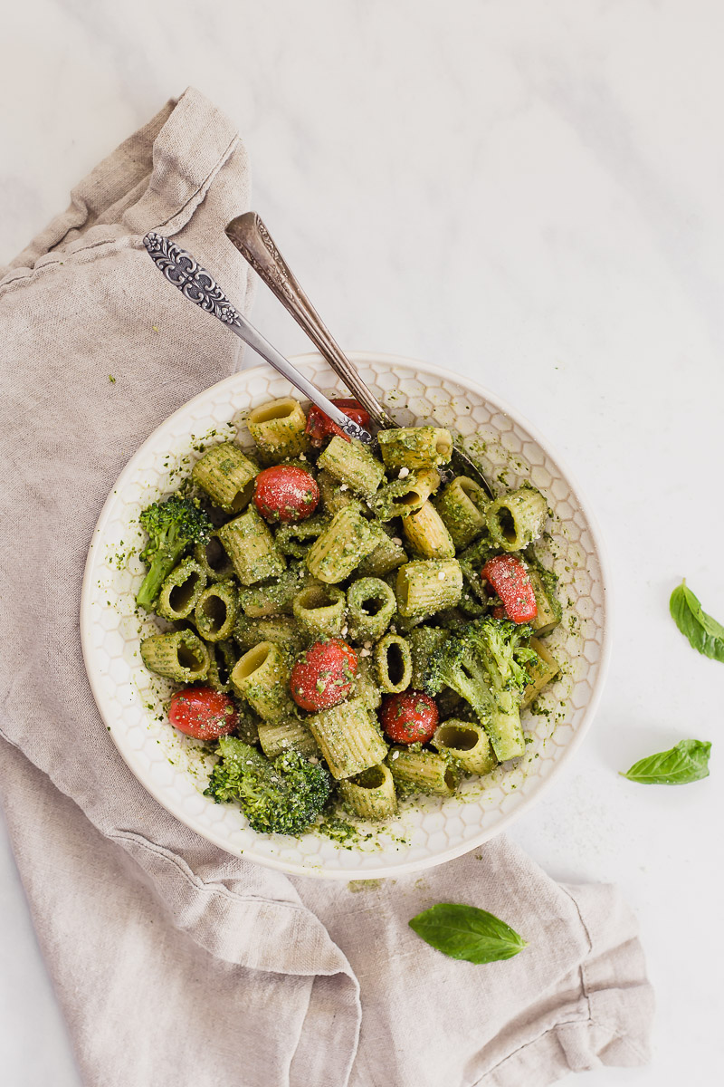 Nut free vegan pesto by Pasta-based. An overhead shot of a bowl of pasta covered in bright green pesto sauce. 