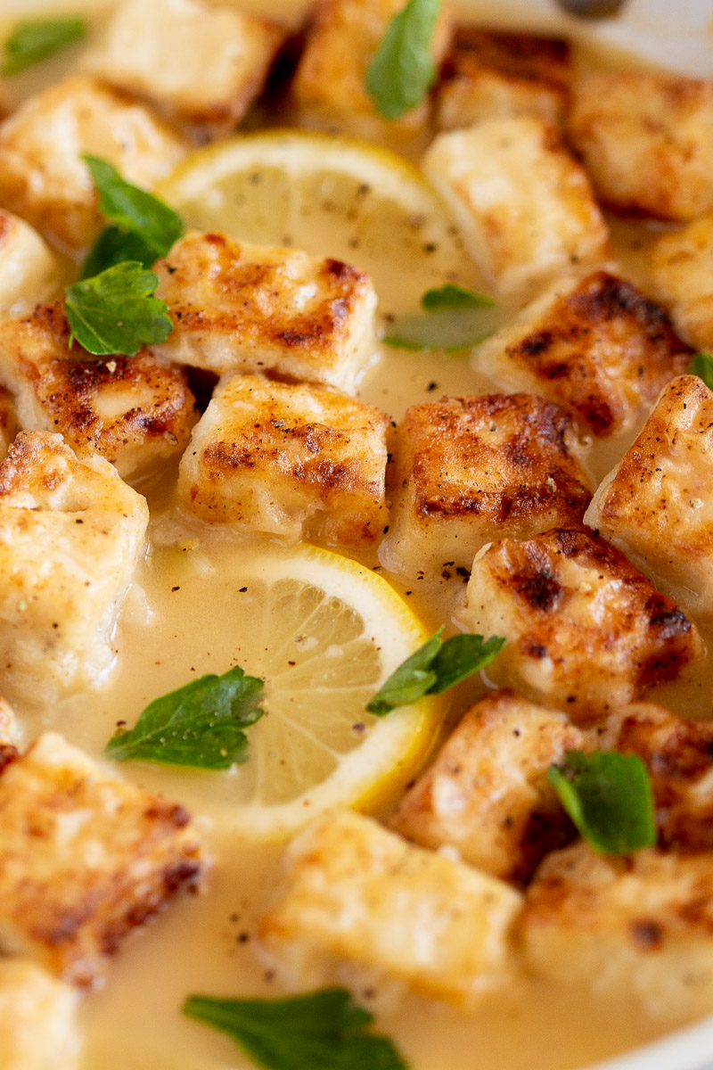 Delicious browned tofu bites, dredged in flour and pan-fried, are resting in a lemony-butter sauce to make Vegan Chicken Francese.