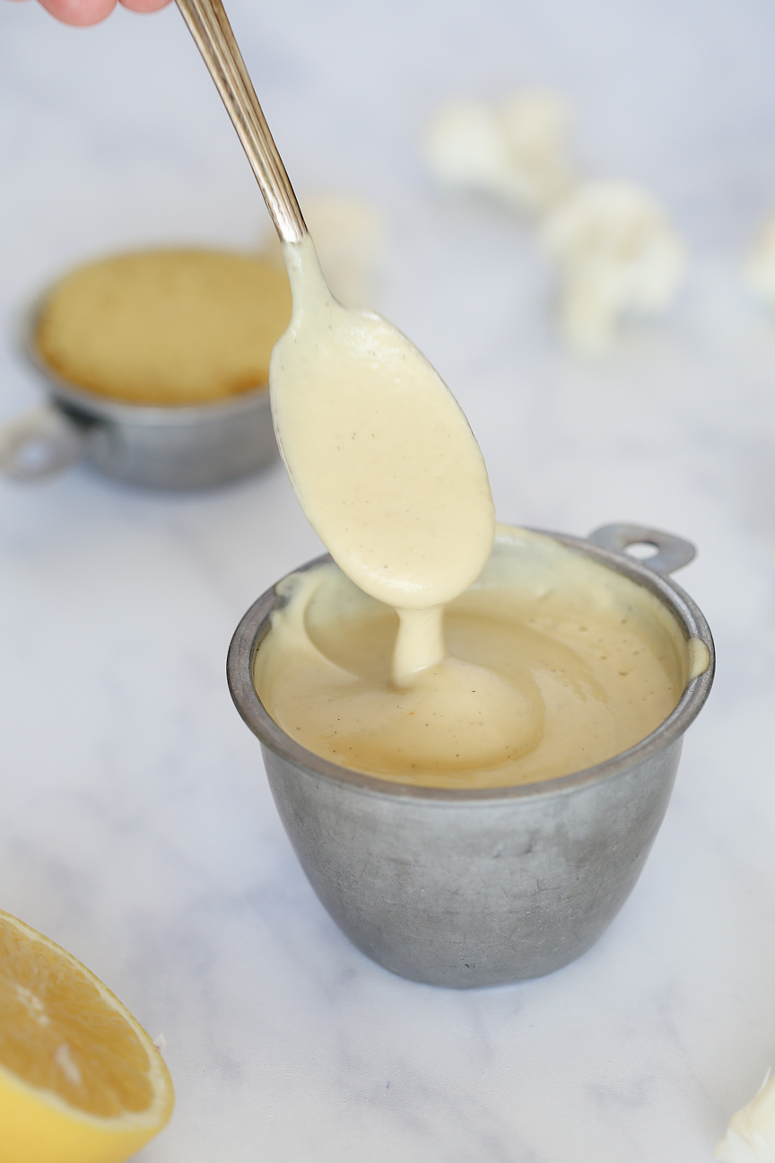 Sauce dripping from a spoon into a silver measuring cup.