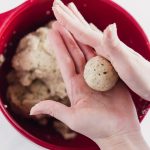 Vegan Brown Rice Meatballs by Pasta-based. A photo of two hands forming a vegan meatball into the perfect ball.