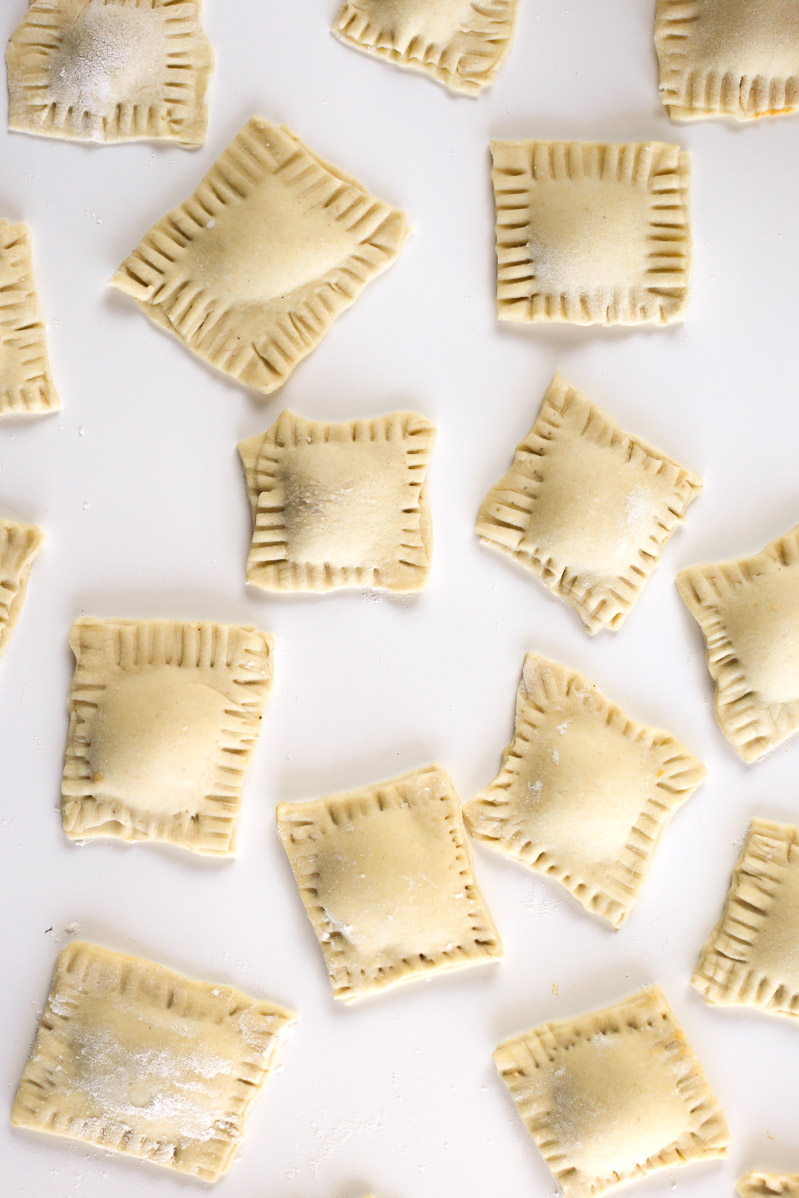 Overhead view of finished butternut squash raviolis, edges crimped with a fork.