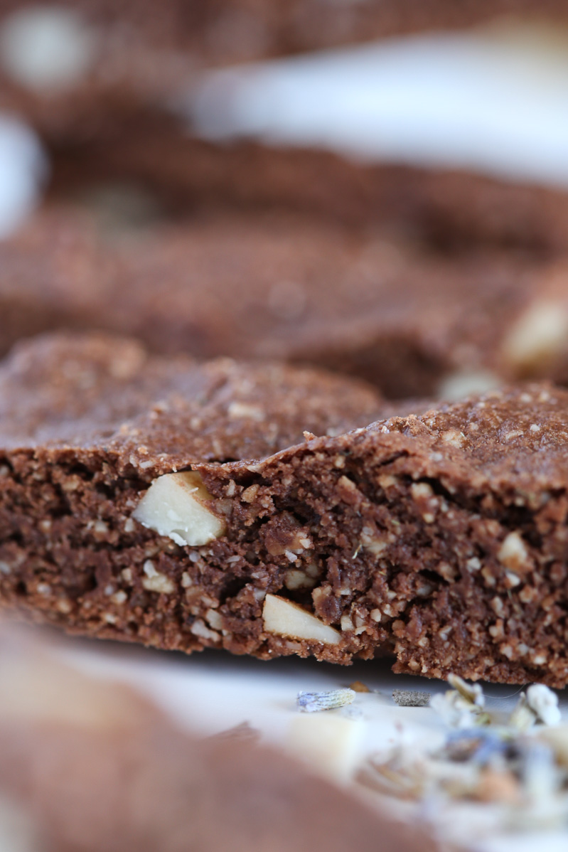 Closer detailed shot of the almond bits within the chocolate lavender biscotti. Lavender buds sprinkled around the table slightly showing in the corner.