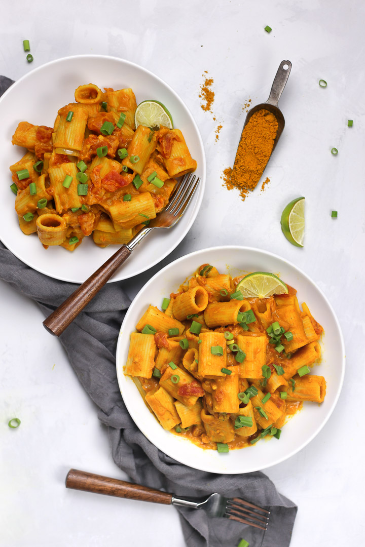 Creamy Vegan Pumpkin Rigatoni Pasta with Pumpkin Puree, Curry Powder, and Coconut Cream, topped with Green Onions and Lime