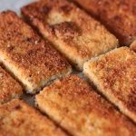 Crispy breaded and pan-fried vegan tofu cutlets lined up in a row. The breadcrumb coating looks golden brown and delicious.