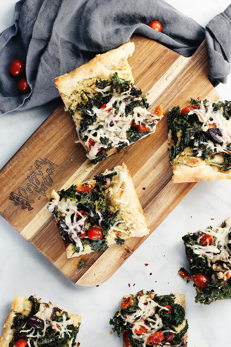 Vegan Crispy Kale Grandma-Style Pizza by Pasta-based. A top-down shot of a few slices of pizza on a table.