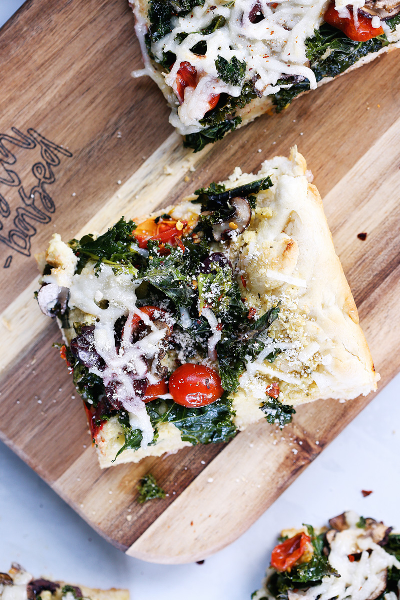 Vegan Crispy Kale Grandma-Style Pizza by Pasta-based. A top-down shot of a square slice of pizza on a cutting board.