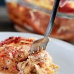 Spaghetti Squash Lasagna (Vegan and Gluten-free) by Pasta-based. Someone is taking a forkful of spaghetti squash lasagna with creamy vegan ricotta cheese melting out.