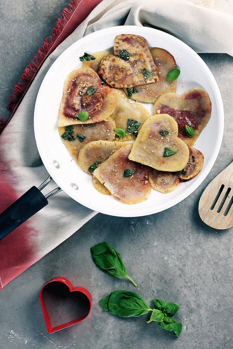 Vegan Red Beet Pesto Ravioli by Pasta-based. Lightly crisped vegan heart-shaped beet pesto ravioli in a skillet.