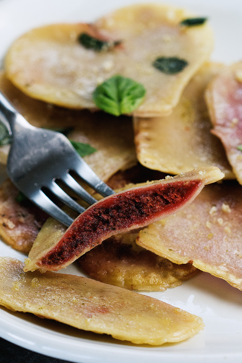 Vegan Red Beet Pesto Ravioli by Pasta-based. Close-up of a ravioli cut open and creamy red beet pesto in the middle.