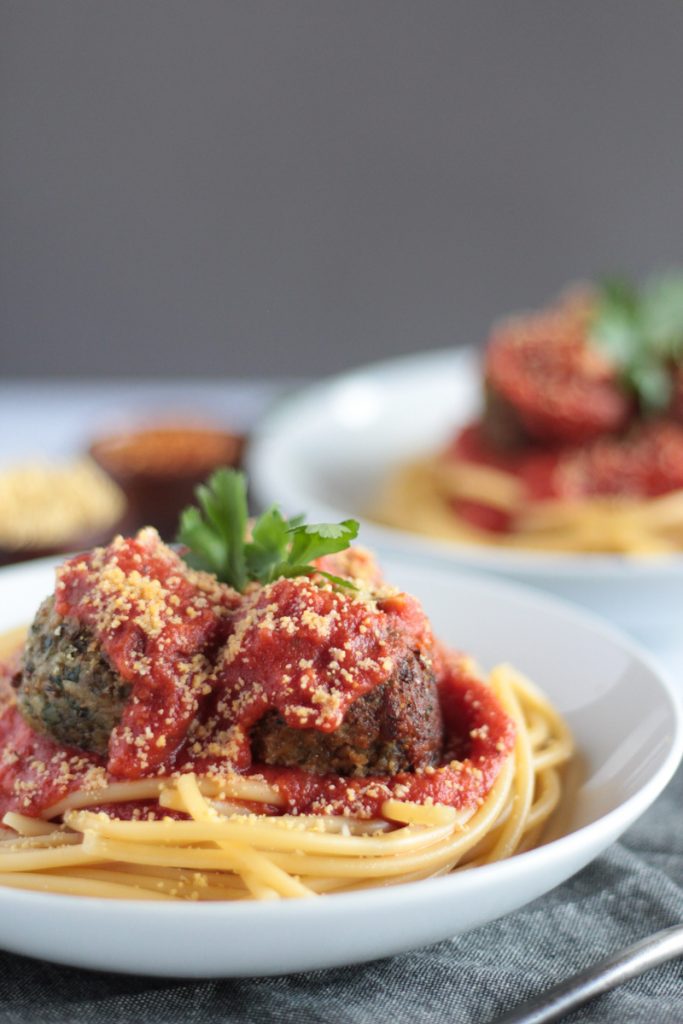 Crispy and browned vegan lentil meatballs on a bowl of spaghetti. Marinara sauce and vegan parmesan cheese on top.