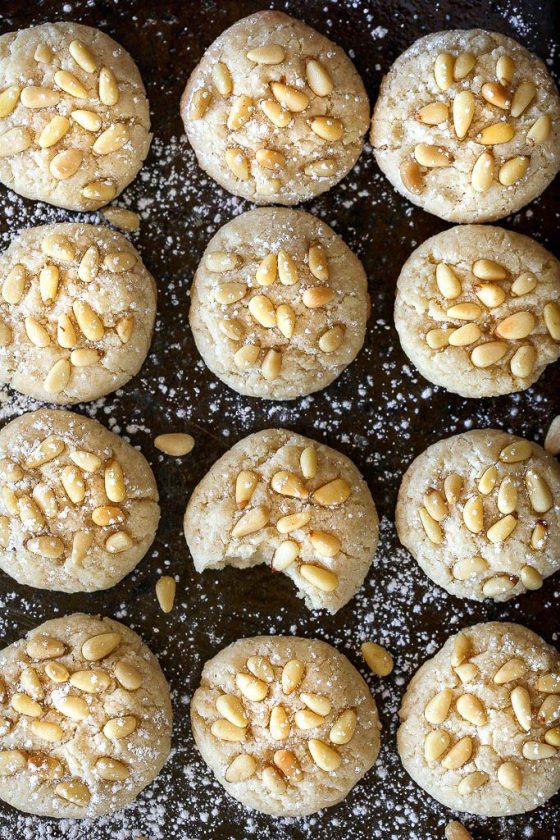 Vegan Italian Pignoli Cookies by Pasta-based. An overhead shot of the baked pignoli cookies on the baking sheet with powdered sugar sprinkled on them.