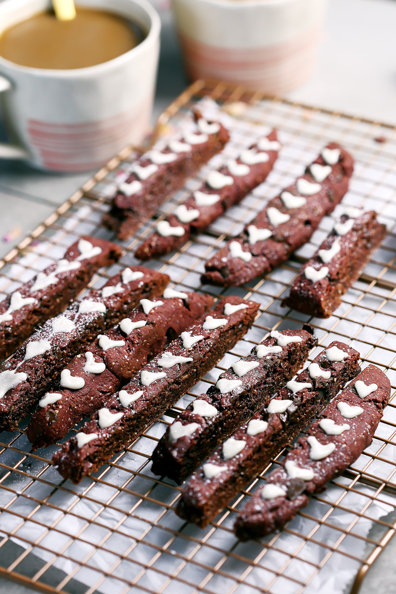 Red Velvet Biscotti by Pasta-based. Laying on a cooling rack, red velvet biscotti with white icing hearts.