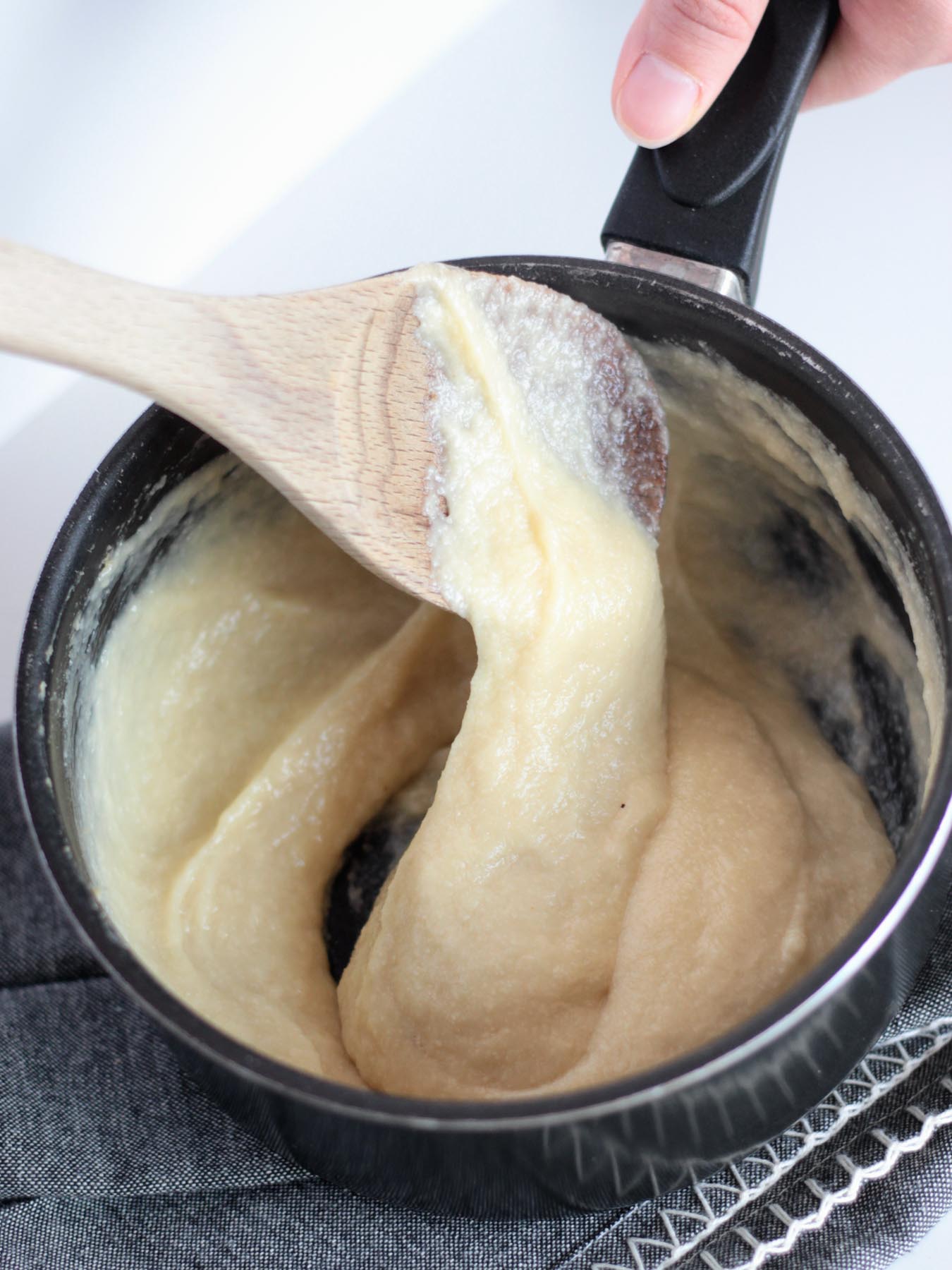 vegan mozzarella cheese shown gooey in a black sauce pan.