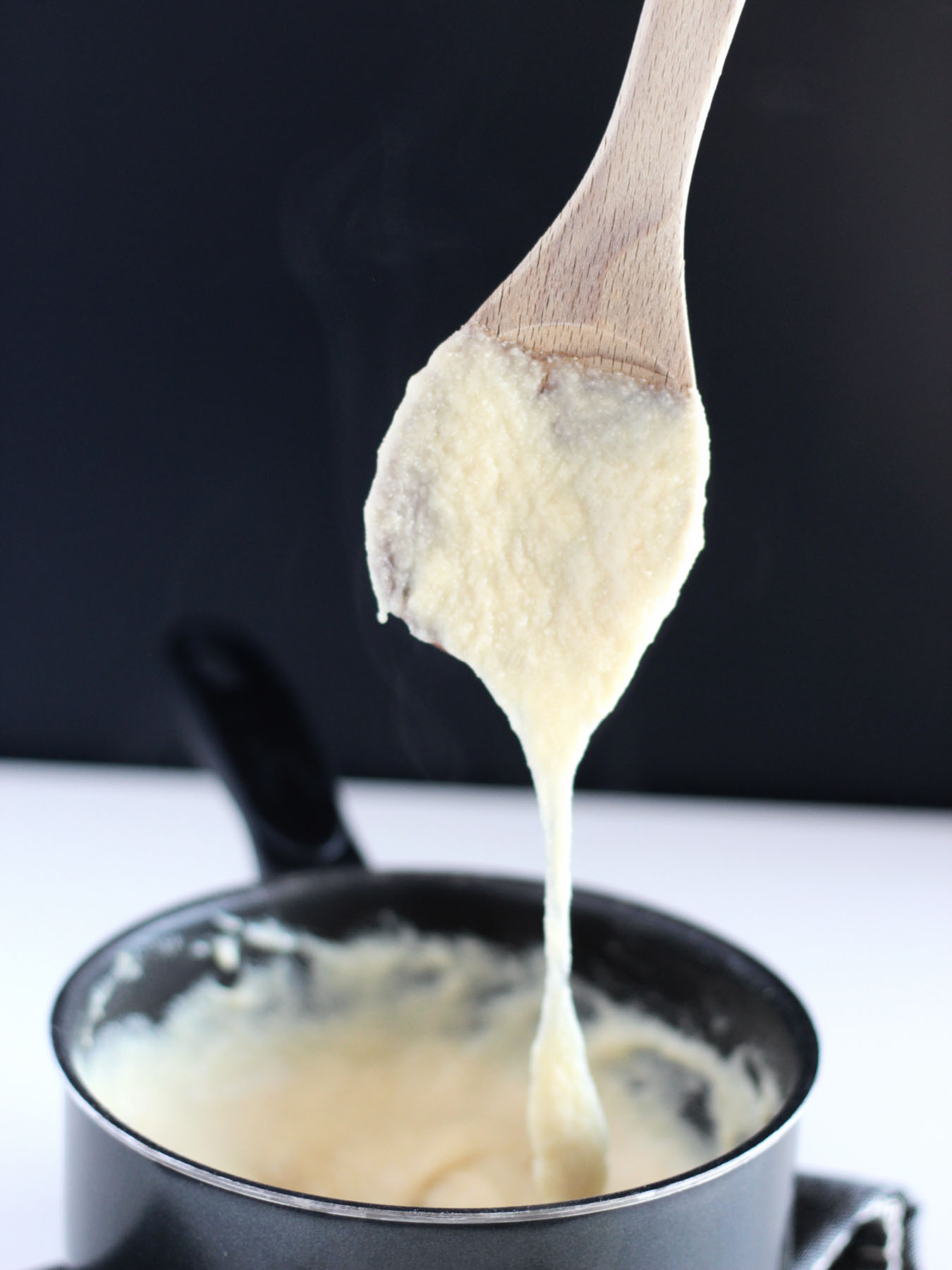 vegan mozzarella cheese shown gooey in a black sauce pan.