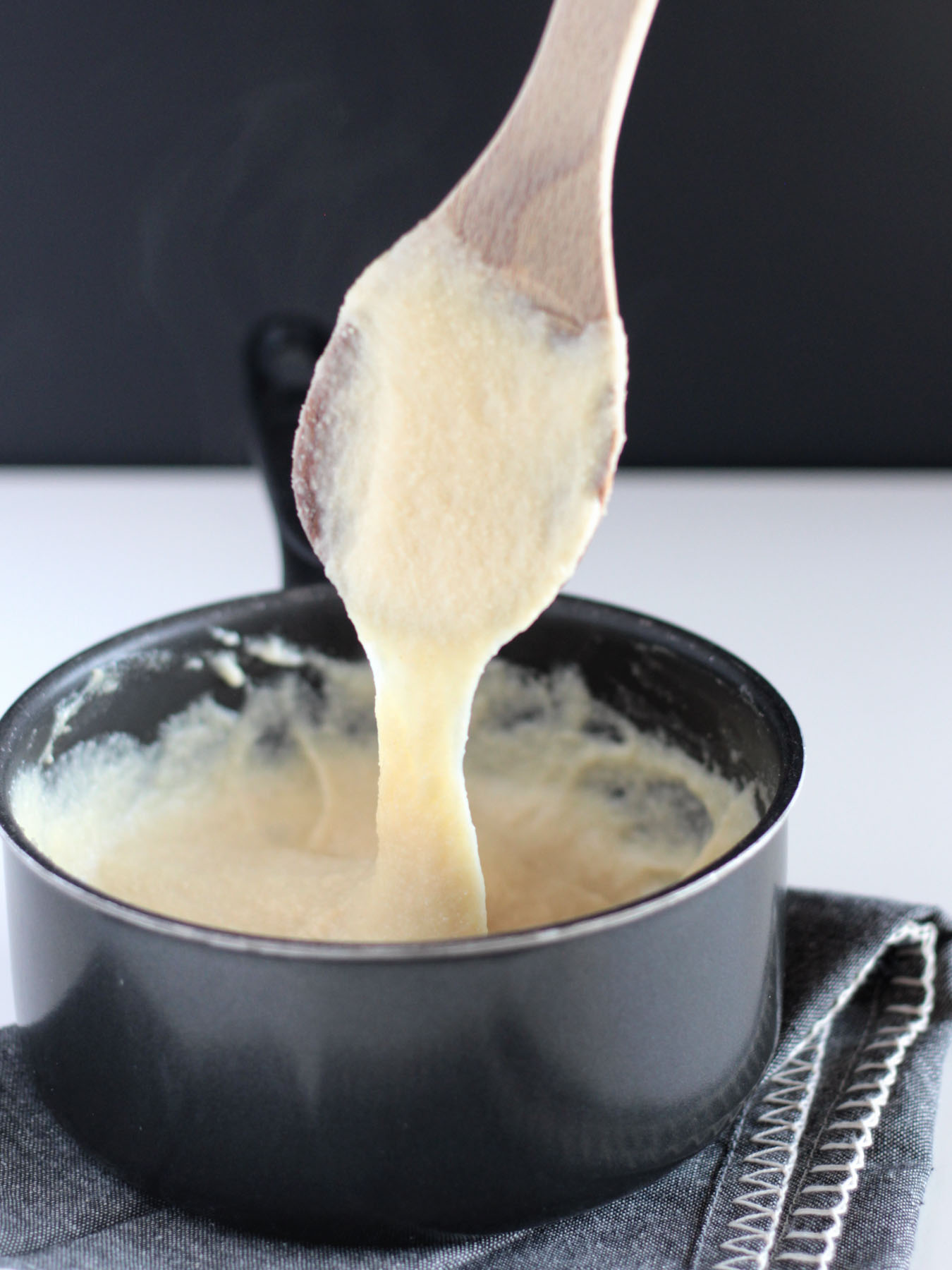 vegan mozzarella cheese shown gooey in a black sauce pan.