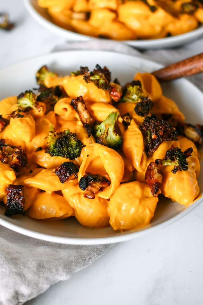 Close up of vegan mac and cheese with vegan tempeh bacon on top and roasted broccoli.